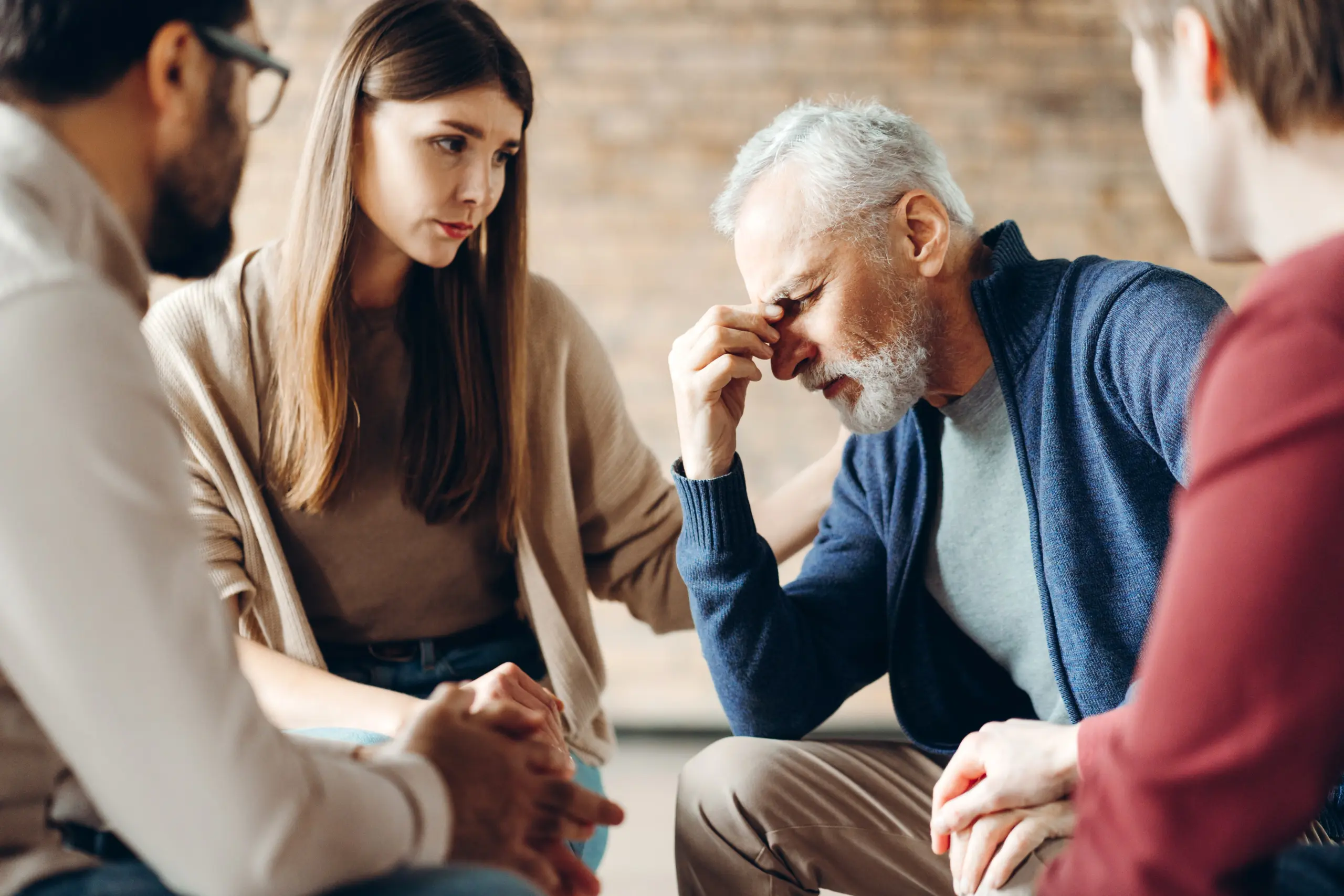 Psychotherapists comforting sad senior man having mental health problems during group therapy session, addiction treatment or team building seminar