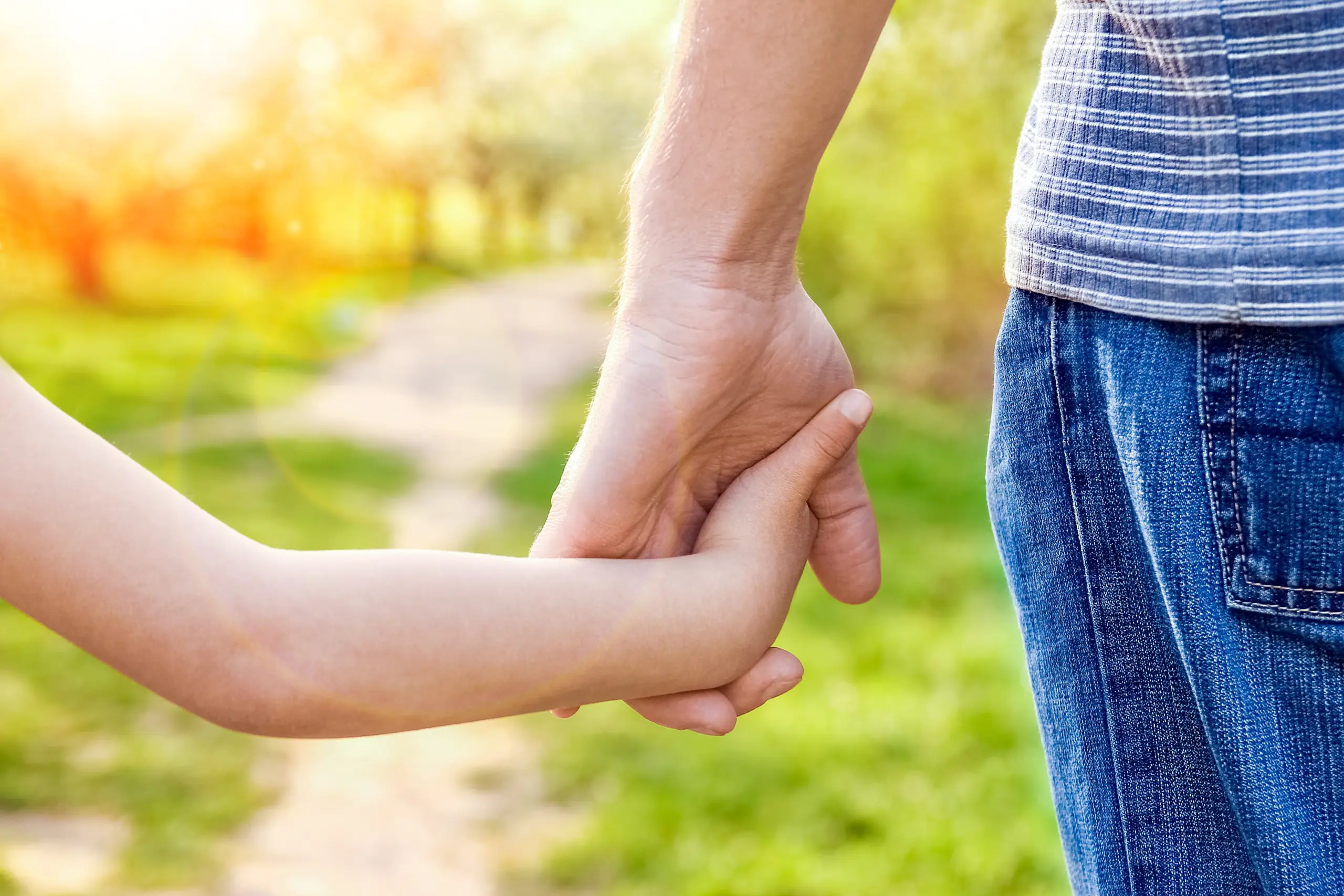 A parent's hand holding a child's hand, symbolizing present and stable sober parenting.