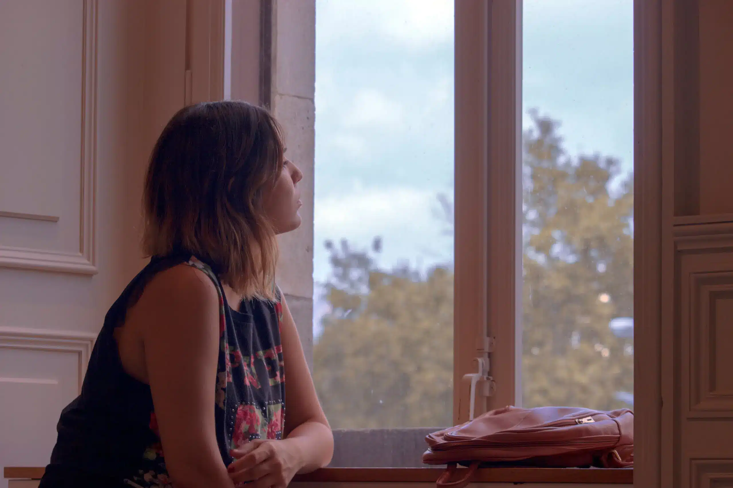 Person sitting quietly by a window experiencing emotional numbness after rehab
